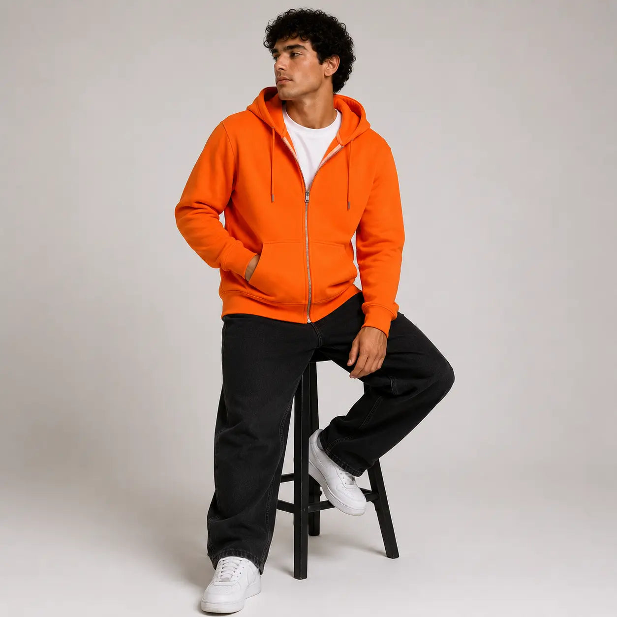 Sudadera con capucha naranja, vista frontal, combinada con camiseta blanca y pantalones oscuros. Casual y cómoda para uso diario.